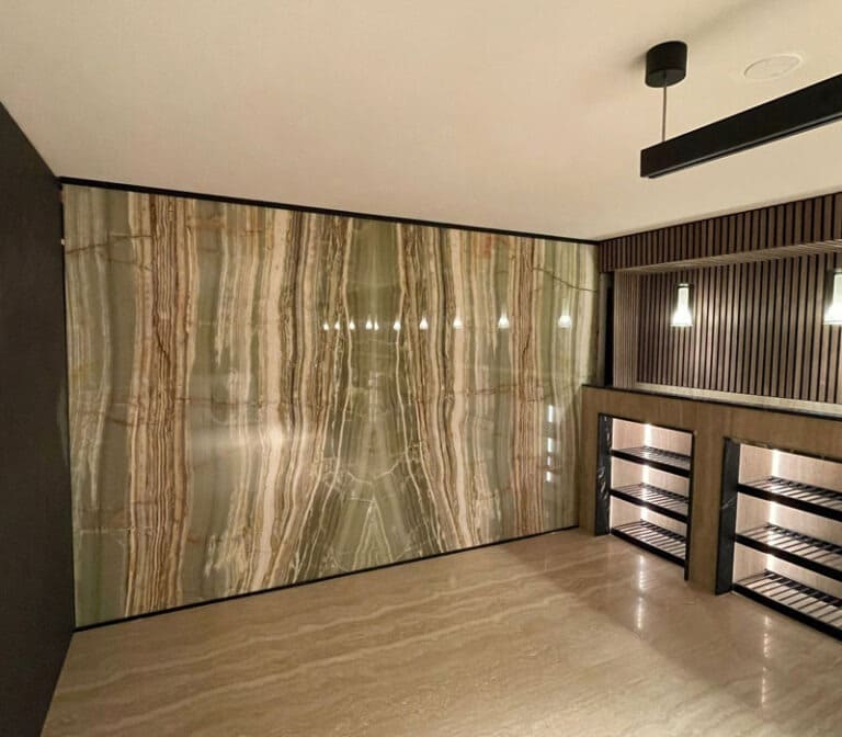 Phòng hiện đại với tường đá hoa văn xanh vân nổi bật, đèn treo trang trí và kệ để rượu sang trọng.