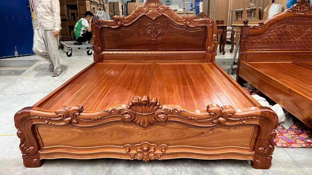 Giường gỗ tự nhiên chạm khắc tinh xảo trong xưởng mộc, thiết kế cổ điển và sang trọng.