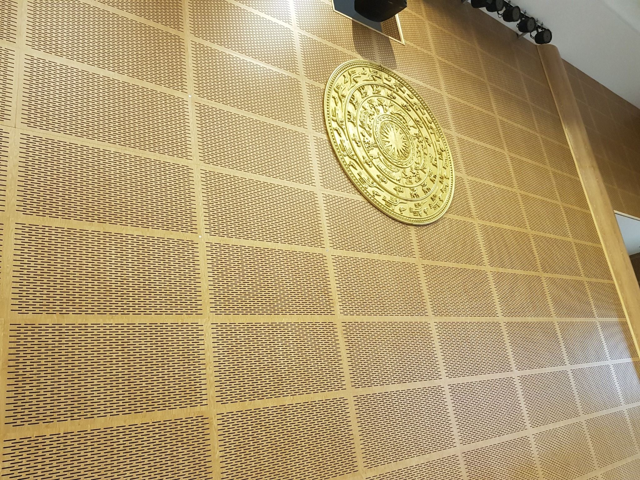 go-tieu-am Tường màu vàng với họa tiết hoa văn và mặt trống đồng, trang trí sang trọng trong không gian nội thất.