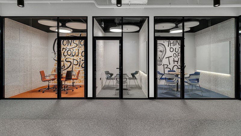 Ba phòng họp hiện đại với bàn ghế, trang trí sáng tạo và vách kính trong suốt.