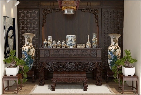 Phòng thờ truyền thống với bàn thờ gỗ, bình gốm trang trí lớn, đèn trần và cây cảnh xanh tươi.