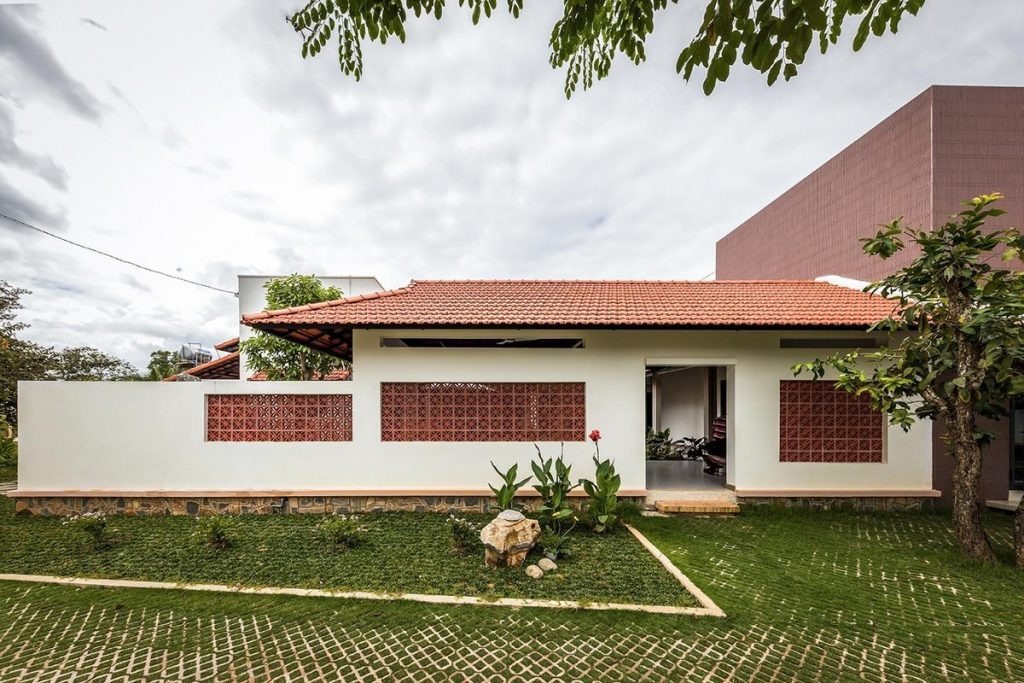 Nhà cấp 4 với mái ngói đỏ, sân vườn xanh mát và cây cảnh bao quanh, thiết kế hiện đại và thoáng đãng.