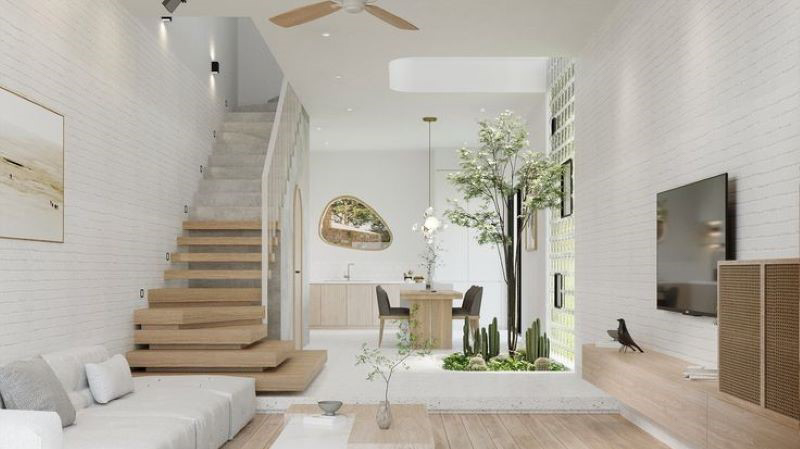 Phòng khách hiện đại với cầu thang gỗ, cây xanh và nội thất tối giản, tạo cảm giác thoải mái và rộng rãi.
