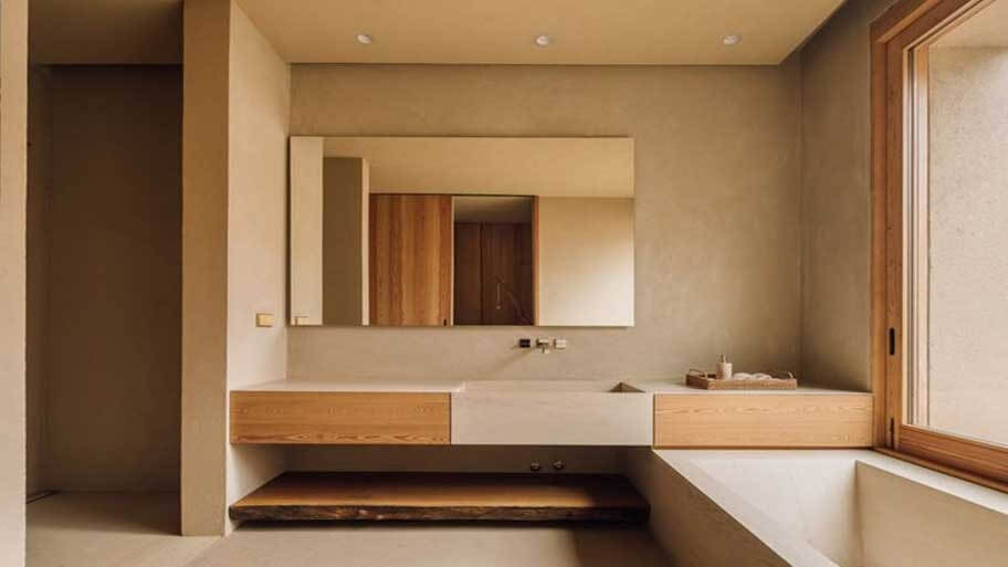 Phòng tắm tối giản với tông màu nâu, gương lớn và cửa sổ kính, tạo cảm giác ấm cúng và hiện đại.