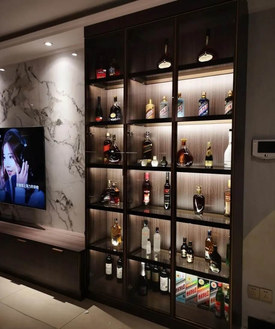 Tủ trưng bày rượu với đèn chiếu sáng và TV trên nền đá cẩm thạch.
