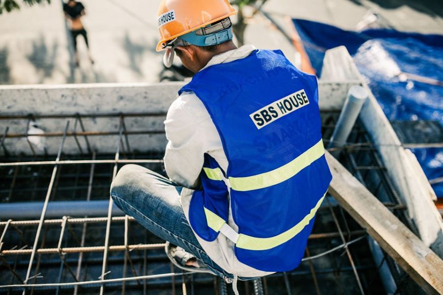 Công nhân xây dựng mặc áo phản quang SBS HOUSE, đội mũ bảo hộ, kiểm tra công trình xây dựng.