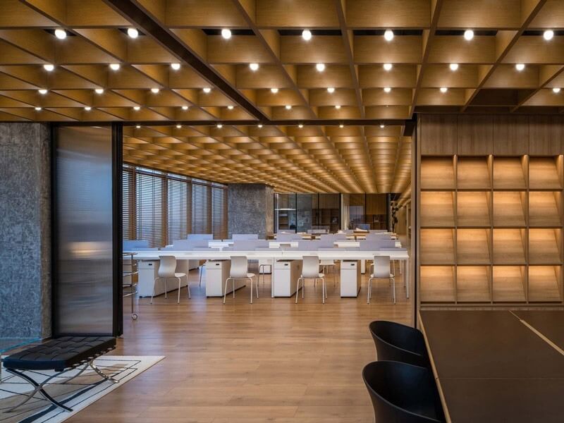 Không gian văn phòng hiện đại với trần gỗ và bàn ghế trắng, ánh sáng dịu nhẹ.