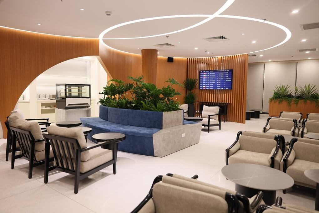 khu-vuc-lounge-duoc-dau-tu Phòng chờ sân bay sang trọng với ghế bành thoải mái, cây xanh và màn hình thông báo thông tin chuyến bay.