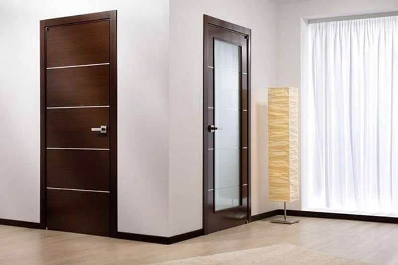 kich-thuoc-cua-phong-ngu-cho-dien-tich-lon Cửa gỗ hiện đại màu nâu trong phòng khách, bên cạnh đèn đứng và rèm cửa trắng.