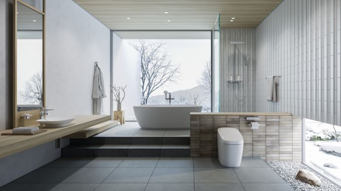 Phòng tắm hiện đại với bồn tắm đứng cạnh cửa kính lớn nhìn ra khung cảnh tuyết rơi ngoài trời.