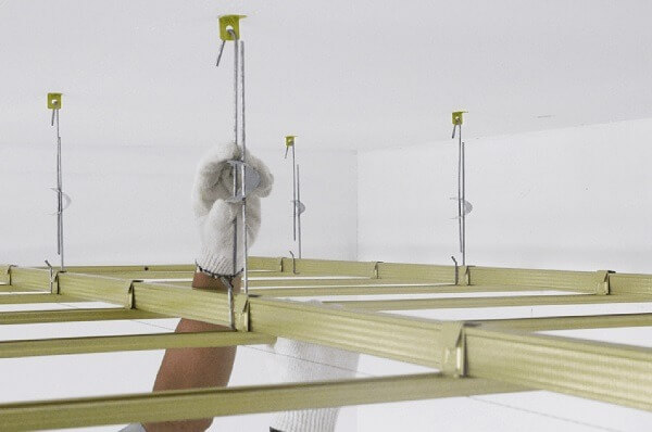 Lắp đặt khung trần nhà bằng thanh kim loại với tay đeo găng bảo hộ trắng.