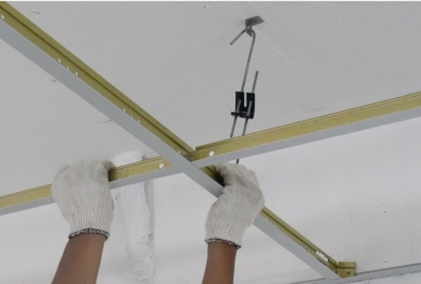 Lắp đặt khung trần thạch cao với đôi tay đeo găng, kỹ thuật xây dựng trần nhà.