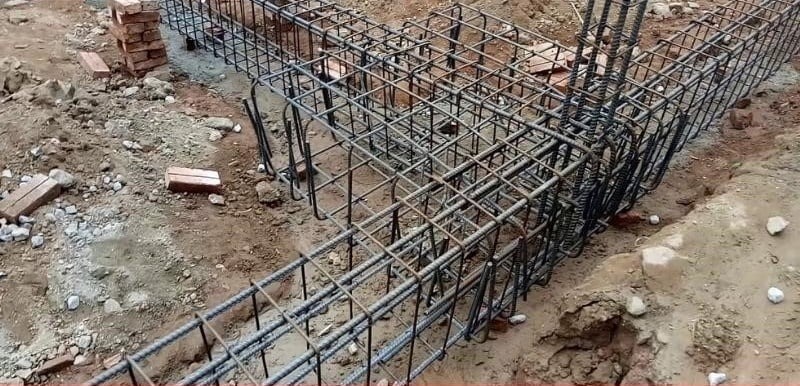 Khung thép xây dựng cho móng nhà trên nền đất, chuẩn bị đổ bê tông để thi công công trình.