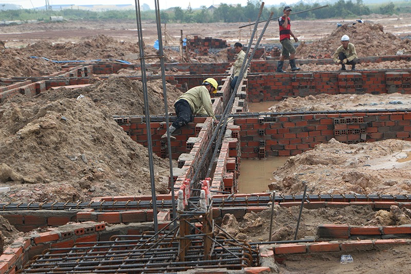 loi-ich-cua-viec-do-mong-nha-duoi-mua-4 Công nhân xây dựng làm việc trên nền móng công trình với gạch và cốt thép, chuẩn bị cho dự án mới.