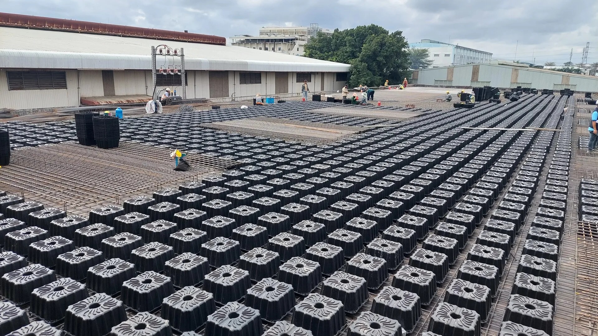 Công trường xây dựng với sàn gạch nhựa định hình và công nhân đang làm việc.