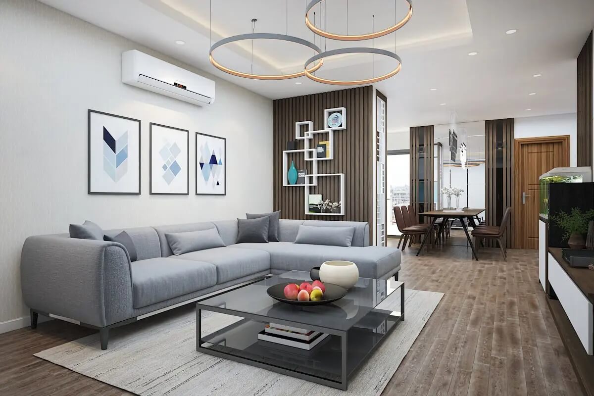 Phòng khách hiện đại với sofa xám, bàn kính, tranh treo tường, và đèn trần vòng tròn. Nội thất tinh tế, không gian mở.