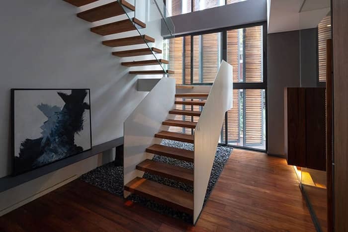 Cầu thang gỗ hiện đại trong không gian nội thất với tranh treo tường và cửa sổ lớn.