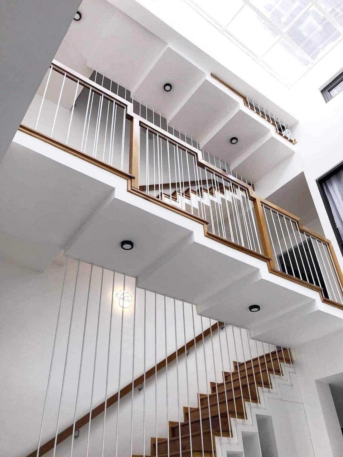 m7vexslno6i2a0dfq8py Cầu thang hiện đại với lan can gỗ và sắt trắng, thiết kế tối giản trong không gian nội thất sáng.