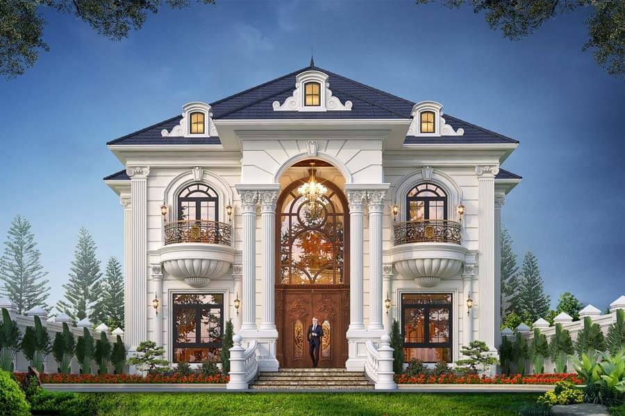 Biệt thự cổ điển sang trọng với mái ngói xanh và tường trắng, cửa sổ lớn và cổng gỗ giữa sân vườn rộng.