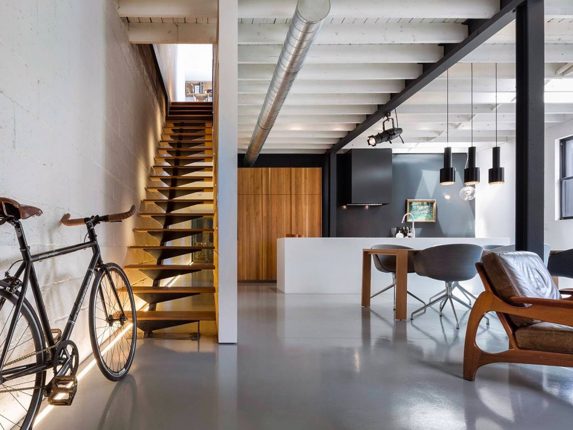 Phòng khách hiện đại với cầu thang gỗ và xe đạp trang trí, không gian tối giản và sang trọng.