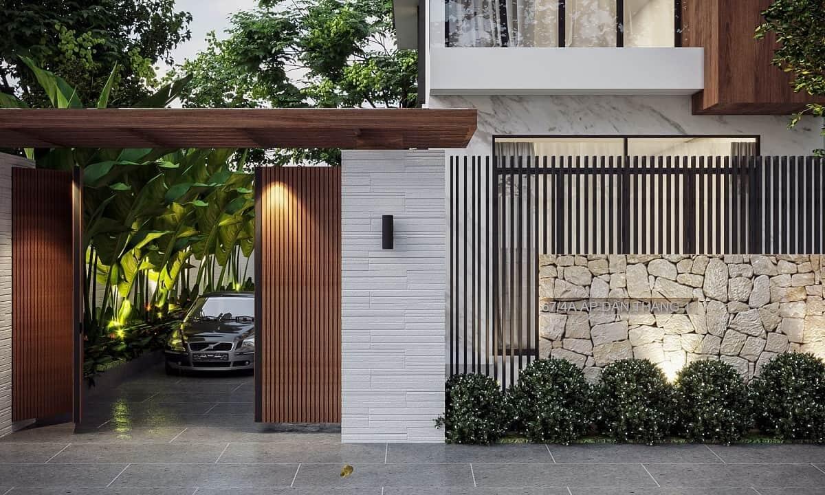 mau-cong-nha-dep-lam-tu-go-3 Nhà hiện đại với cổng gỗ, xe hơi đậu trong sân, tường đá trang trí và cây xanh xung quanh.