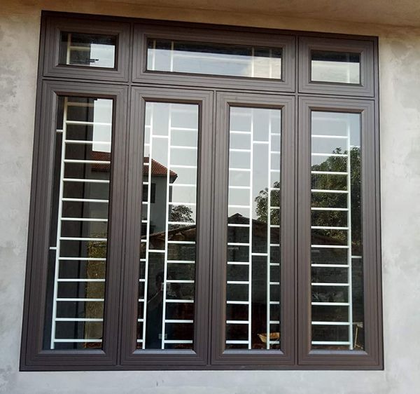 Cửa sổ kính lớn với khung kim loại màu nâu và hoa văn hình chữ nhật, nhìn ra ngoài trời.