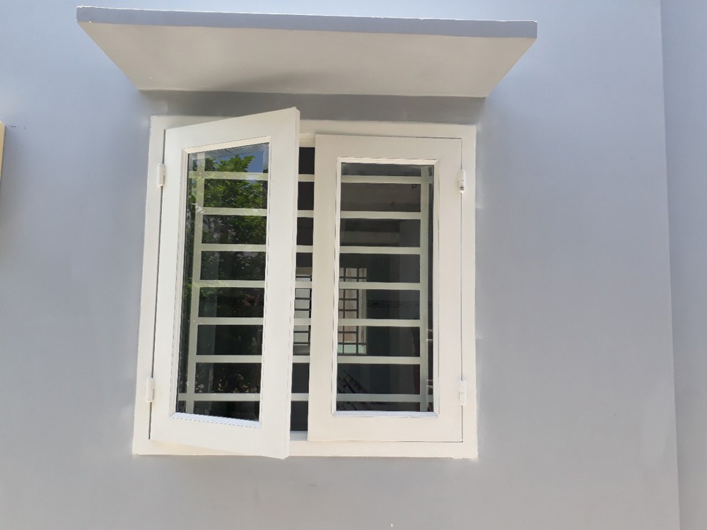 Cửa sổ kính trắng mở ra ngoài với khung kim loại sáng bóng trên tường xám.