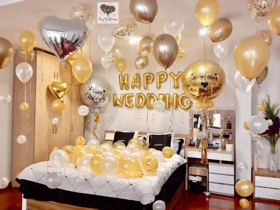 Phòng ngủ trang trí bóng bay vàng kim cho tiệc cưới, dòng chữ Happy Wedding nổi bật.