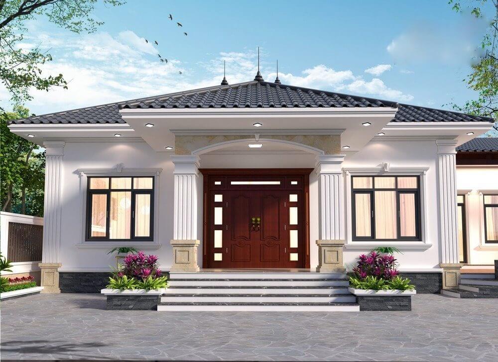 Nhà cấp 4 mái Thái hiện đại với cột trụ và cửa gỗ, sân lát đá và cây xanh xung quanh.