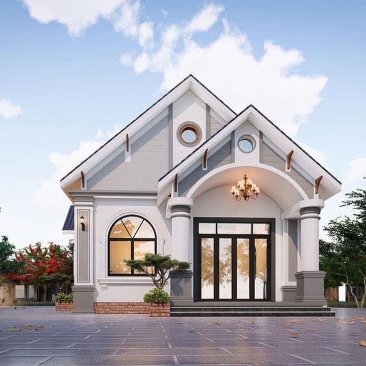 Ngôi nhà phong cách hiện đại với mái vòm, cửa kính lớn, cột trụ trang trí, cây xanh xung quanh và bầu trời xanh sáng.