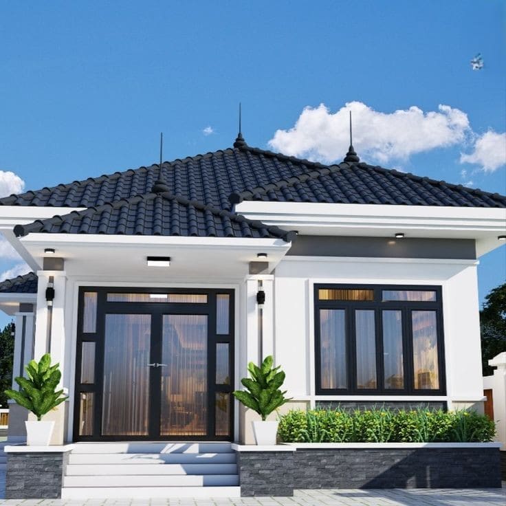 Nhà cấp 4 hiện đại với mái ngói đen, cửa kính lớn và cây xanh trước mặt.