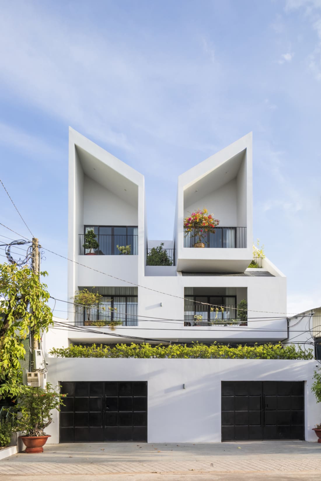 mau-nha-ong-2-tang-lech-3 Ngôi nhà hiện đại với mái lạ mắt, cây cối trang trí ban công và bầu trời xanh.