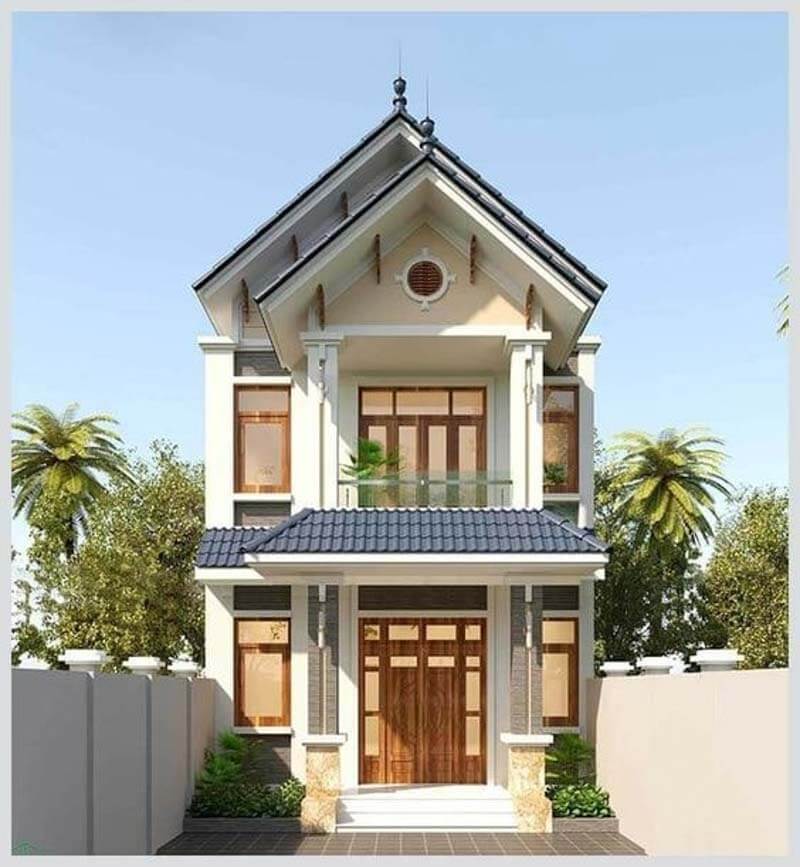 Ngôi nhà hai tầng hiện đại với mái ngói xanh và cửa gỗ, xung quanh là cây cối xanh tươi tạo cảm giác bình yên.