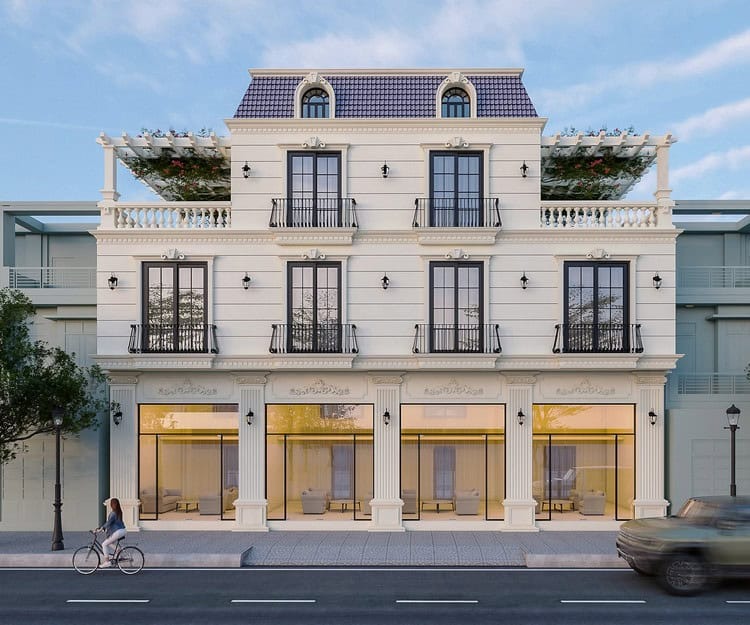 Tòa nhà kiến trúc sang trọng, ba tầng với cửa sổ lớn, ban công có giàn hoa xanh, người đi xe đạp trên vỉa hè.