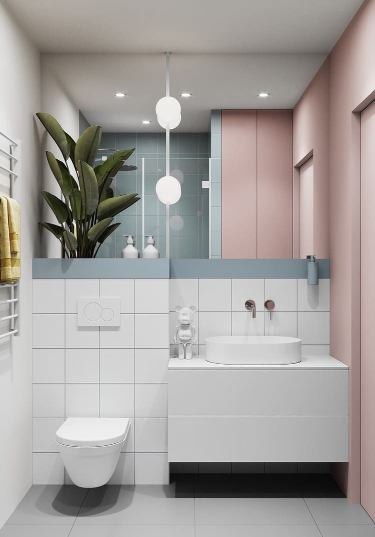 Phòng tắm hiện đại với gạch ốp trắng, lavabo tròn, cây xanh, ánh sáng tinh tế và tường màu hồng pastel.