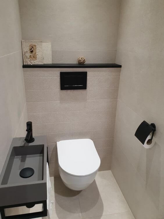 Nhà vệ sinh hiện đại với bồn cầu treo tường và bồn rửa nhỏ, thiết kế tối giản với tông màu trung tính.