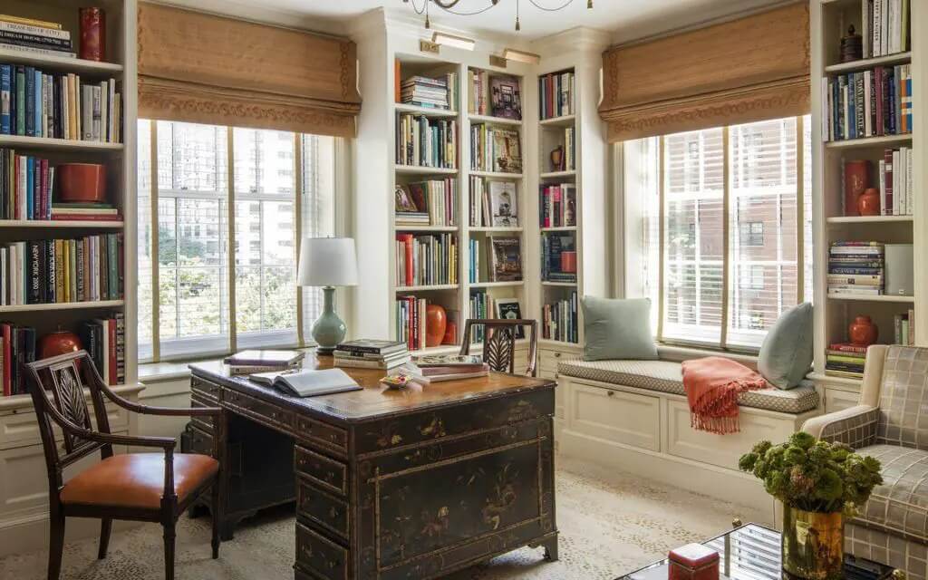 Phòng làm việc tại nhà với bàn cổ điển, kệ sách và cửa sổ lớn đón ánh sáng.