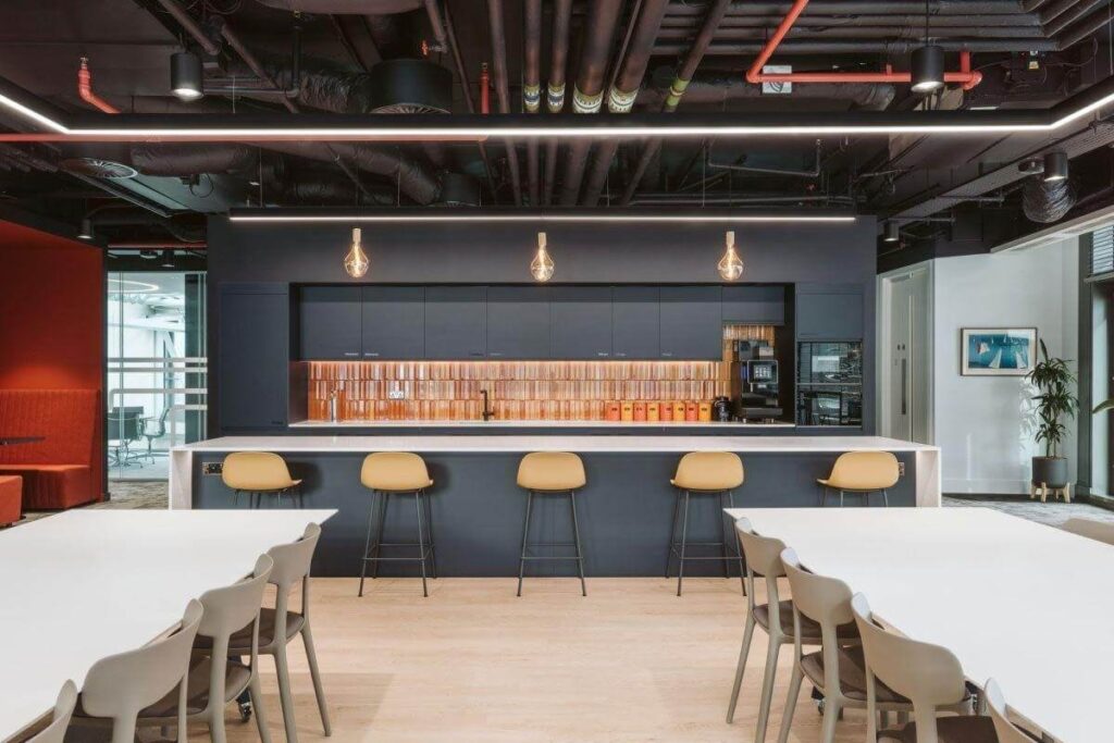 Nhà bếp văn phòng hiện đại với quầy bar, ghế cao và đèn treo, tông màu gỗ và đen.