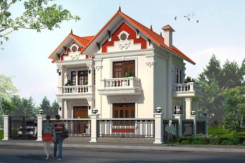 Nhà biệt thự sang trọng, hai tầng, mái ngói đỏ với ban công rộng, có hàng rào thép và cây xanh xung quanh.