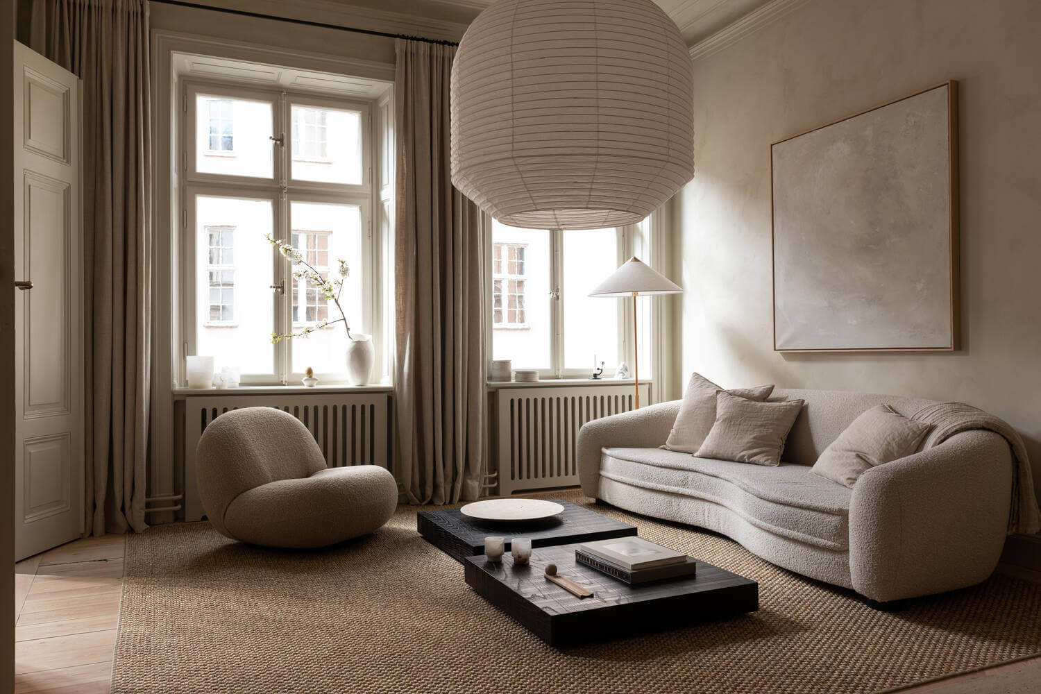 Phòng khách phong cách tối giản với sofa, ghế bành, bàn cà phê và đèn độc đáo, tông màu trung tính.