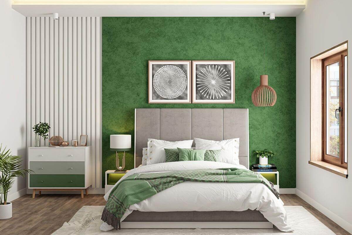 Phòng ngủ hiện đại với tường xanh, giường xám, trang trí tranh và cây cảnh, ánh sáng tự nhiên từ cửa sổ.