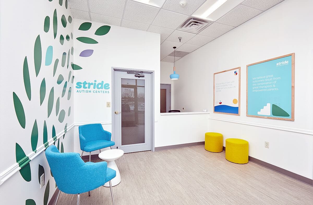 Phòng chờ thoải mái tại Stride Autism Centers với ghế xanh và tranh tường nghệ thuật.