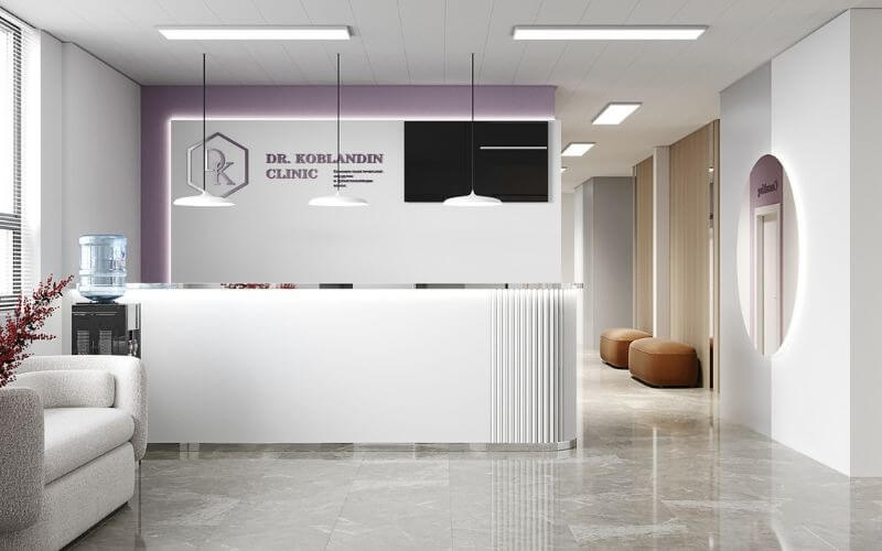 Phòng tiếp tân hiện đại tại phòng khám với bàn trắng, đèn treo, ghế sofa và bình nước.