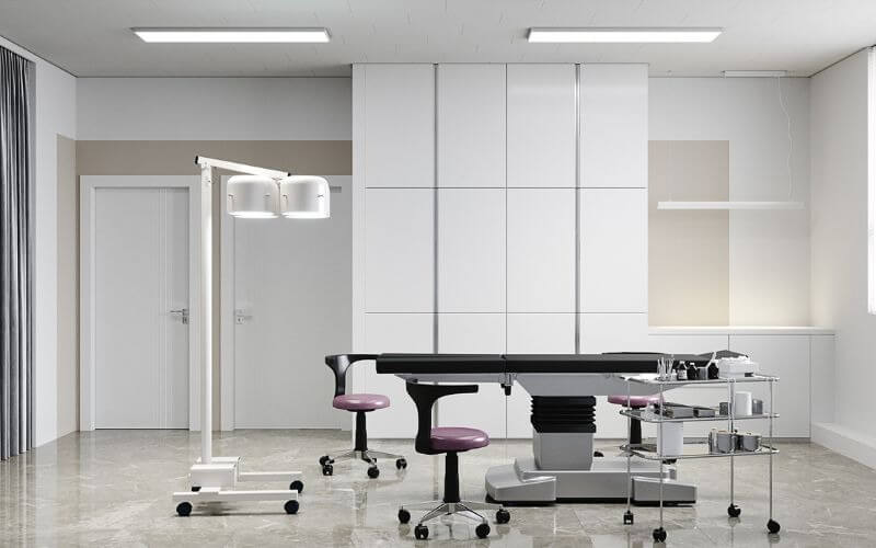 Phòng phẫu thuật hiện đại với giường mổ, ghế xoay và hệ thống chiếu sáng chuyên dụng.