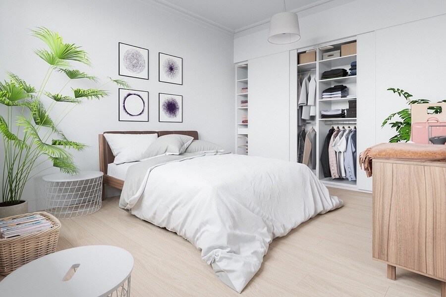 Phòng ngủ hiện đại với giường trắng, tủ quần áo mở và cây xanh trang trí, tạo cảm giác thoải mái và rộng rãi.