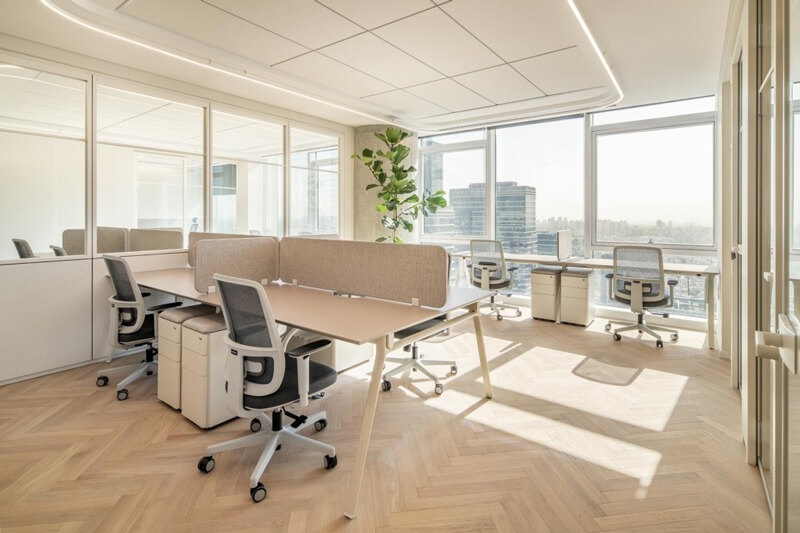 Văn phòng làm việc sáng sủa với bàn ghế hiện đại, cửa sổ lớn và sàn gỗ thanh lịch.
