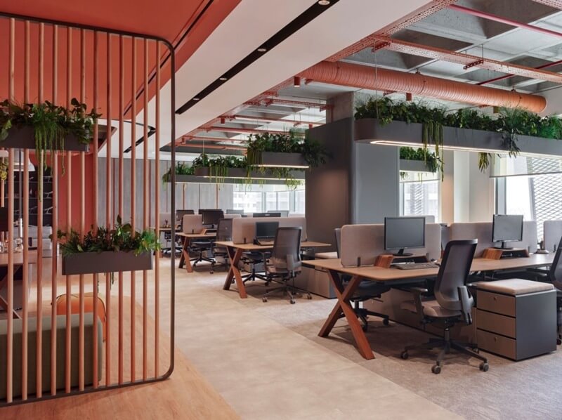 Văn phòng hiện đại với không gian mở, nội thất gỗ, cây xanh trang trí, và ánh sáng tự nhiên từ cửa sổ lớn.