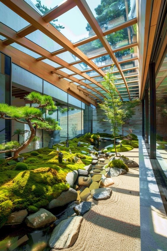 Khoảnh sân vườn Zen trong nhà với cây xanh, đá và cát dưới mái kính, tạo không gian thư giãn thanh tịnh.