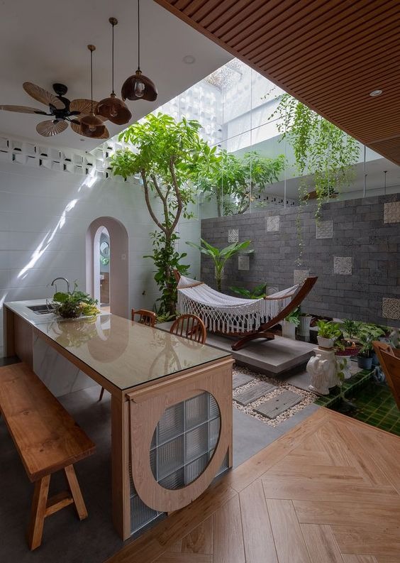 Nhà bếp thiết kế mở với võng trong không gian xanh và bàn ăn hiện đại, ánh sáng tự nhiên chan hòa.