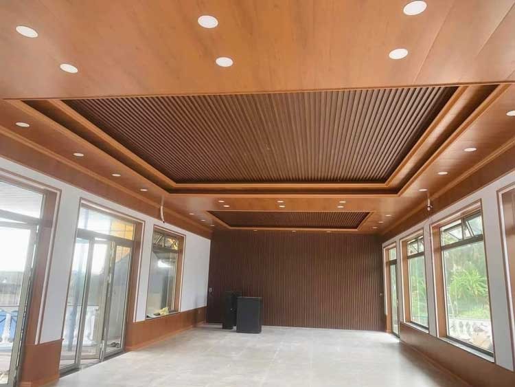 Phòng khách hiện đại với trần gỗ, đèn LED âm trần và cửa kính lớn nhìn ra ngoài trời.